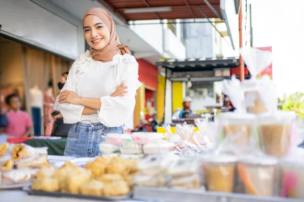 Seorang gadis cantik berkerudung dengan tangan kusut menjual berbagai macam makanan goreng — Stok Foto