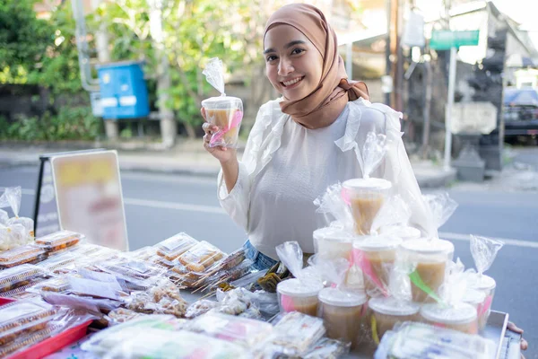 Une fille dans un voile tient takjil nourriture remplie de kolak dans une tasse en plastique — Photo