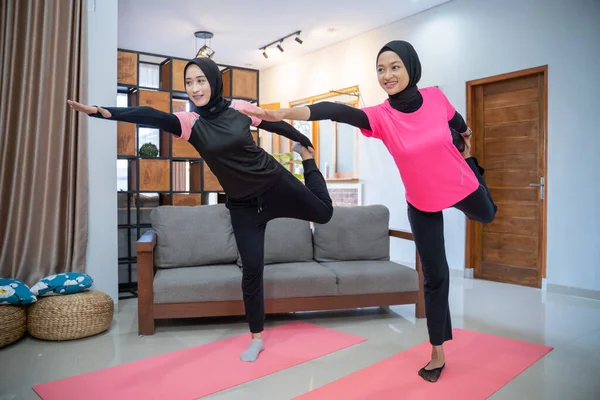 Deux femmes portant un foulard souriant tout en faisant des mouvements de fentes tout en exerçant à l'intérieur — Photo