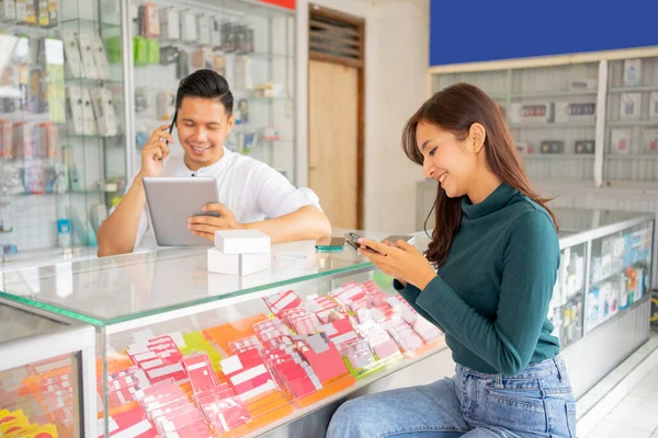 Vrouw zit in de buurt van een winkel tijdens het typen van een bericht met behulp van een mobiele telefoon — Stockfoto