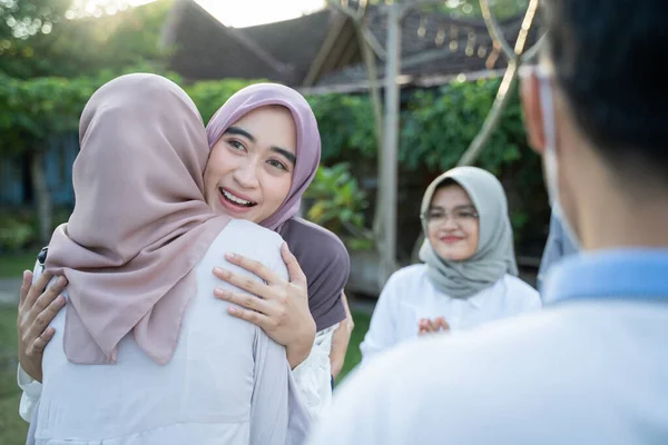 Een vrouw draagt een hoofddoek knuffelt een gesluierde vrouw tijdens een bijeenkomst — Stockfoto