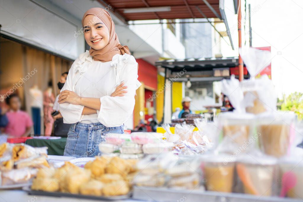 a beautiful girl in a veil with crosed hands selling various kinds of fried foods