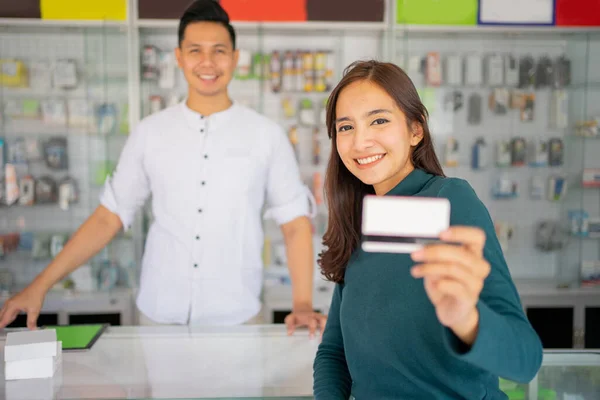 Primer plano de un hermoso cliente femenino muestra una tarjeta de crédito para el pago sin efectivo — Foto de Stock