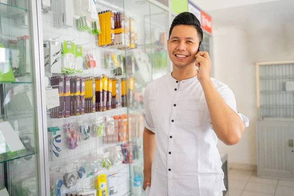 Joven hombre de negocios haciendo una llamada con un teléfono celular en una tienda de teléfonos celulares —  Fotos de Stock