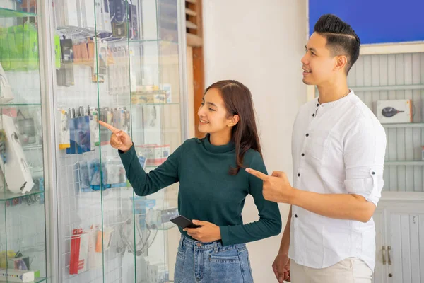 Uma mulher asiática e homem de pé apontando para uma vitrine — Fotografia de Stock