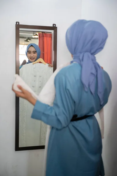 Seorang wanita dalam kerudung mencoba pada jubah di depan cermin — Stok Foto