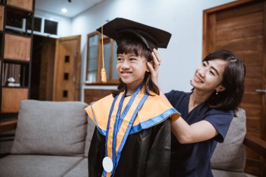 Asyalı anne ve çocuk evde daha iyi bir mezuniyet gününe hazırlanıyor.