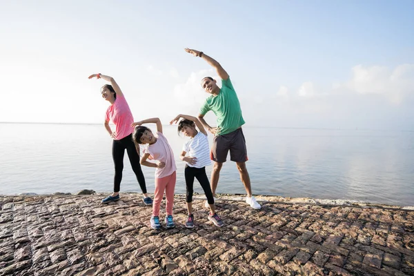 Asiatische Eltern und Kinder dehnen sich am Strand — Stockfoto