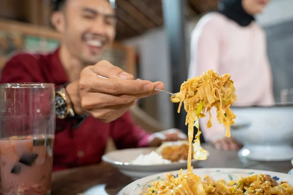 Close up of a mans hand using a fork taking fried nudle — Stock fotografie