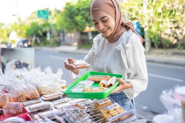 Egy gyönyörű lány egy fejkendőben, kezében egy műanyag tálcával, hogy elhelyezze a választékot az ételeket vásárolt — Stock Fotó