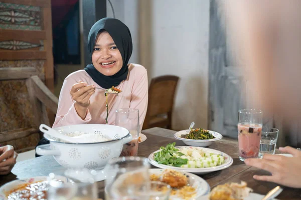 Žena se závojem se usmívá, když používá lžíci, když se chystá jíst jídlo — Stock fotografie