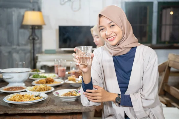 Eine verschleierte Frau lächelt in die Kamera und hält ein Glas, um gemeinsam das Fasten zu brechen — Stockfoto