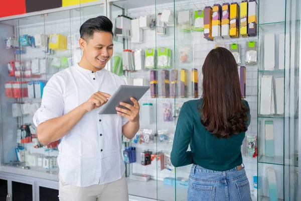 Affärsman med hjälp av en tablett och en kvinna tittar på och välja tillbehör produkter — Stockfoto