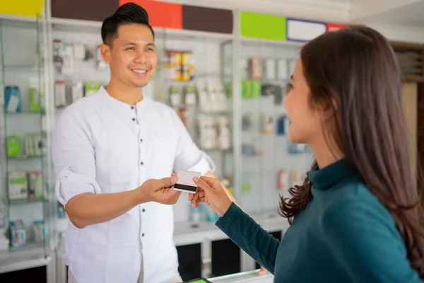 Close-up de uma cliente feminina dando um cartão de crédito para um homem para pagamento sem dinheiro — Fotografia de Stock