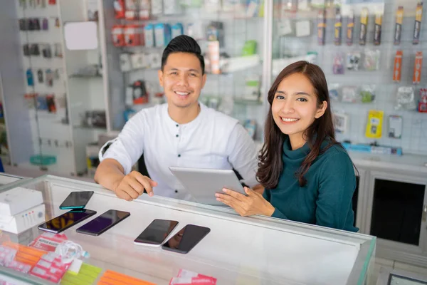 A business woman and a business man smiling at the camera while using a tablet together — Stock Photo, Image