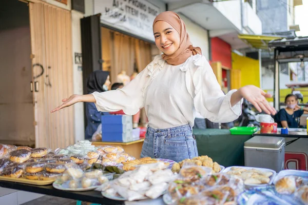 美しい女の子を笑顔でヒジャーブで手のジェスチャーを提供する様々な揚げ食品 — ストック写真