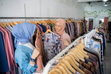 Güzel bayan garson bayan müşterilere servis yaparken güzel elbiseler gösteriyor.