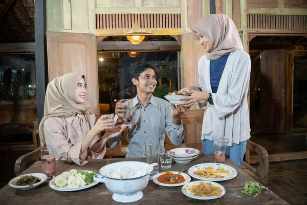 Dua wanita memakai jilbab dan seorang pria asia merapikan meja makan setelah iftar bersama-sama — Stok Foto