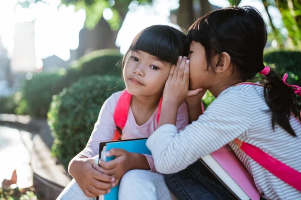 Bambina studentessa sussurrando al suo amico. — Foto Stock