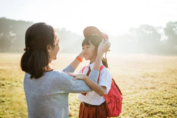 Mother fixing her daughter primary school student uniform — Stock Photo, Image