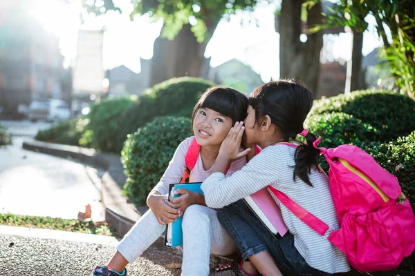 Niña estudiante susurrando a su amigo. — Foto de Stock