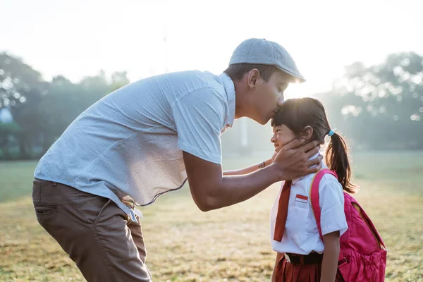 Отец целует дочь в лоб, когда отвозит ее в школу утром — стоковое фото