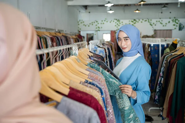 Podnikatelka s modrým závojem za použití tabletu při držení oblečení — Stock fotografie