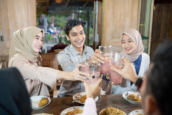 Tiga orang muda merayakan dan mengangkat gelas es buah untuk bersulang selama iftar bersama-sama — Stok Foto