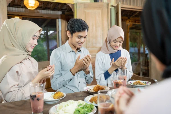 Un hombre musulmán y una mujer velada rezan juntos antes de comer —  Fotos de Stock