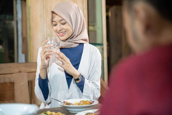 Seorang wanita berkerudung tersenyum memegang gelas sambil minum untuk iftar — Stok Foto