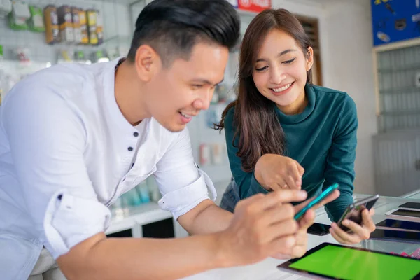 Une belle fille sourit en pointant vers l'écran du téléphone portable d'un employé de magasin masculin — Photo