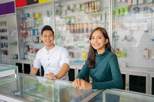 Ein junger Mann und eine junge Frau, die hinter einer Vitrine in die Kamera lächeln — Stockfoto