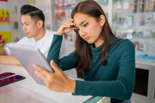 Una triste mujer de negocios que enfrenta algunos problemas mientras usa una tableta al lado de un hombre —  Fotos de Stock