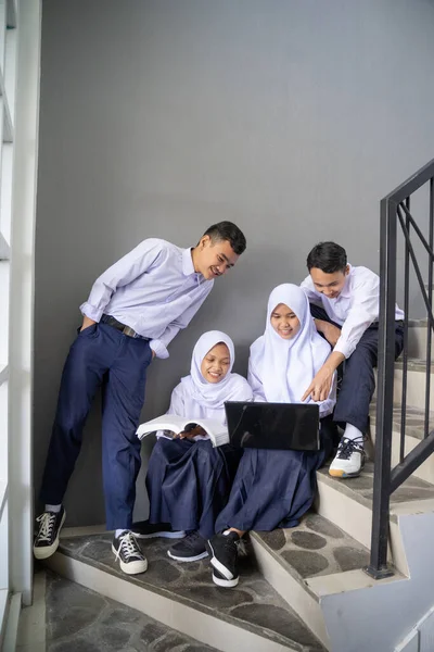 Empat remaja berseragam SMP berbagi laptop — Stok Foto