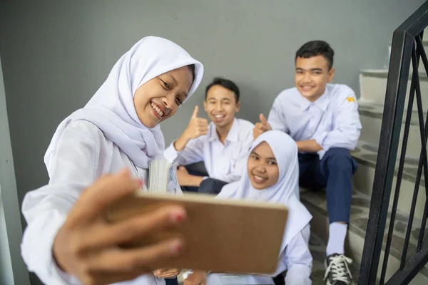 Um grupo de adolescentes em uniformes escolares tomando selfies junto com um celular — Fotografia de Stock