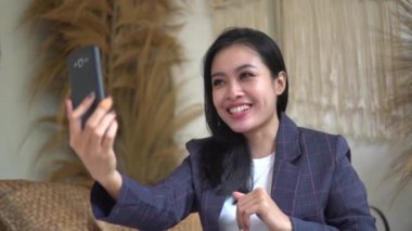 Spor ceketli bir iş kadını video görüşmesi ya da video kaydı için akıllı telefon kullanıyor.