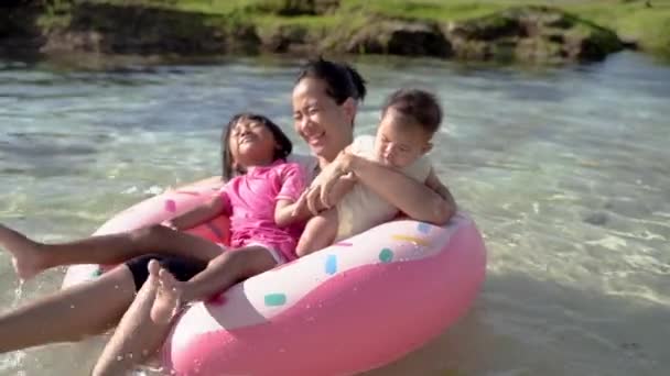 Мать и двое ее детей смеются, когда едут на буевом кольце — стоковое видео