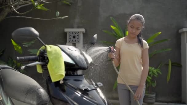 Asian young girl washing his motorcycle scooter with water — Stock Video