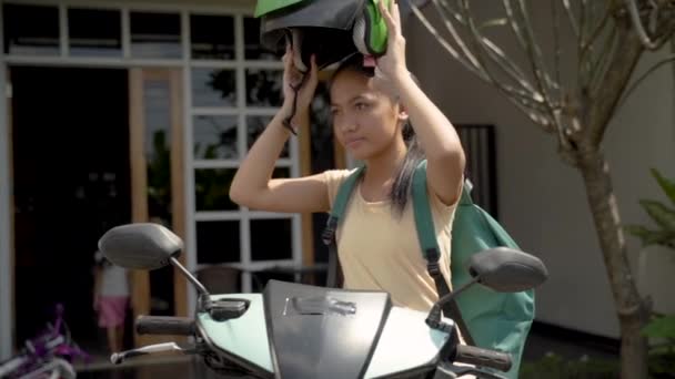 Hermosa joven está sentada en su motocicleta con casco en casa — Vídeo de stock