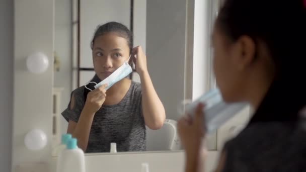 Nahaufnahme von Teenager-Mädchen trägt eine Maske, während sie vor dem Ausgehen sitzt — Stockvideo