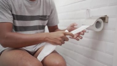 Tuvalette elinde mendille oturan adam.