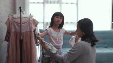 Asyalı anne kızıyla butik giyim mağazasında alışveriş yapıyor.