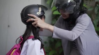 Anne sabah kızını motosikletle okula götürüyor.