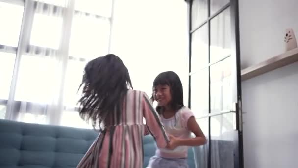 Happy cute asian small girls sister or friends having fun playing together in kitchen. Two funny children circling, jumping, singing in livingroom — Stock Video