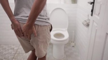 male with stomach ache having a diarrhea standing in toilet and hands hold his butt