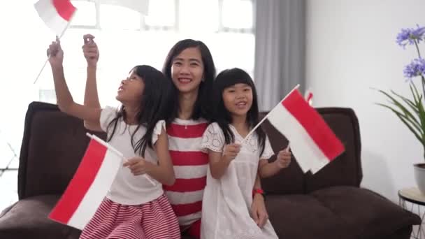 Mor och dotter firar indonesisk självständighetsdag hemma bär rött och vitt med indonesisk flagga — Stockvideo