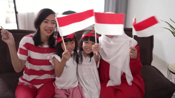 Moeder en dochter vieren Indonesische onafhankelijkheidsdag thuis met rood en wit aan de vlag van Indonesië — Stockvideo