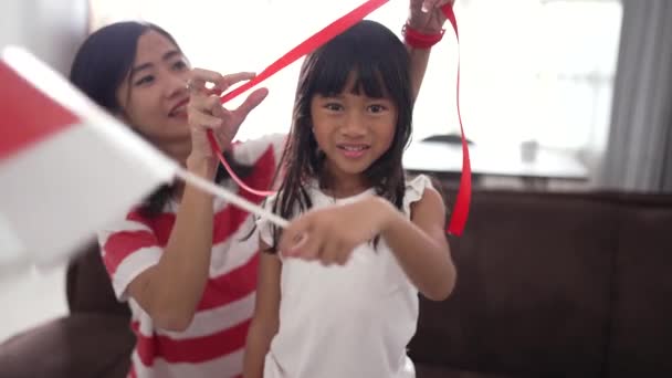 Mom tying red ribbon on her daughters forehead — Wideo stockowe