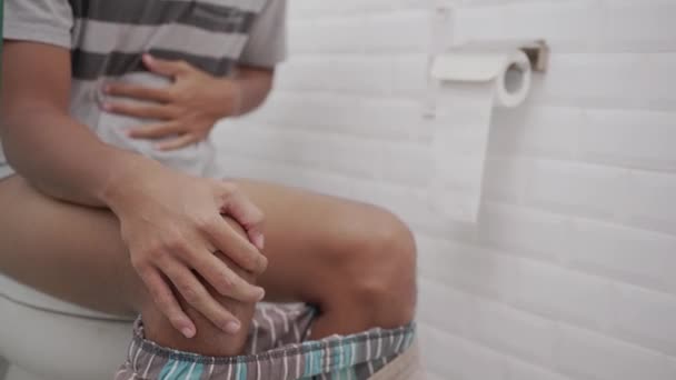 Male with stomach ache having a diarrhea in toilet and hold his belly painfully. — Stockvideo