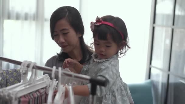 Krásná asijské matka přičemž její dcera koupit oblečení — Stock video